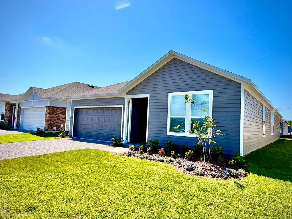 A single-story house with gray horizontal siding, a two-car garage, and a front lawn — 5111 NATALIA DRIVE, ST CLOUD, FL