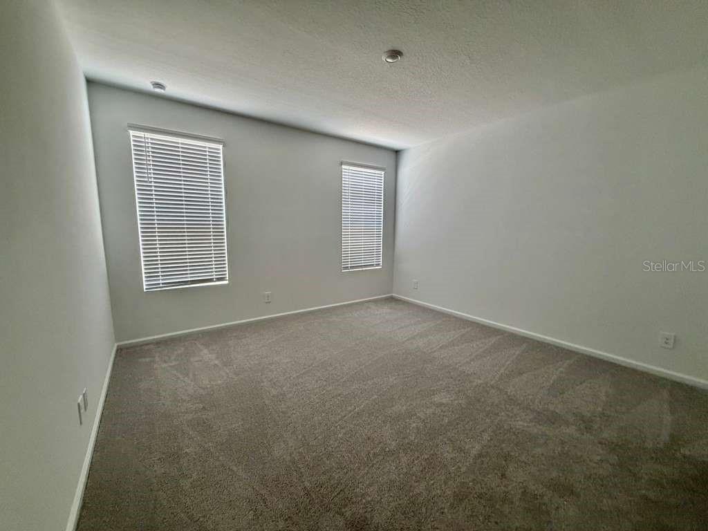 An empty bedroom features gray walls, beige carpeting, and two windows with white blinds — 5111 NATALIA DRIVE, ST CLOUD, FL