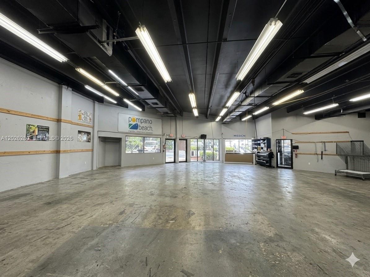 An open commercial space features a concrete floor, exposed ceiling, and fluorescent lighting — 590 SW 9th Ter # 11, Pompano Beach FL 33069, POMPANO BEACH, FL