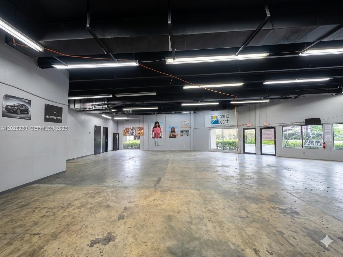 An empty commercial space features a concrete floor, exposed ceiling, and large windows — 590 SW 9th Ter # 11, Pompano Beach FL 33069, POMPANO BEACH, FL