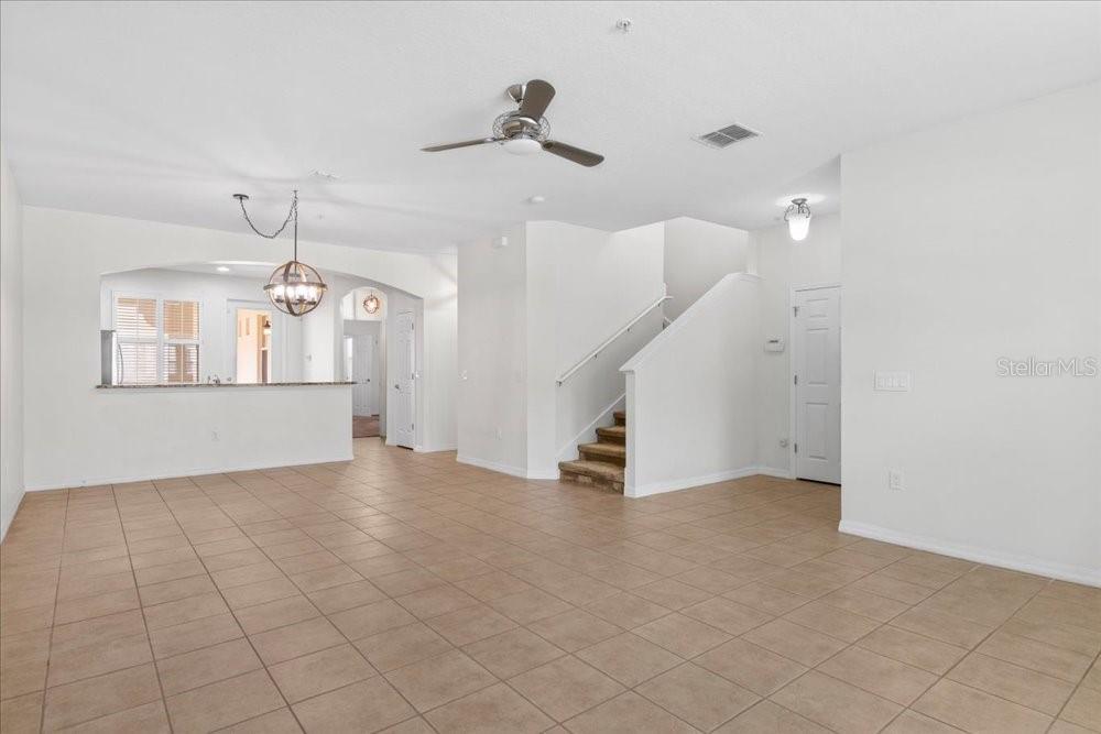 An open-concept living area features tile flooring, a staircase, and a kitchen pass-through window — 2958 AQUA VIRGO LOOP UNIT 52, ORLANDO, FL
