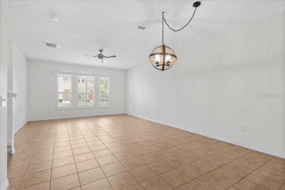 An empty room features tile flooring, a ceiling fan, and a hanging orb chandelier — 2958 AQUA VIRGO LOOP UNIT 52, ORLANDO, FL