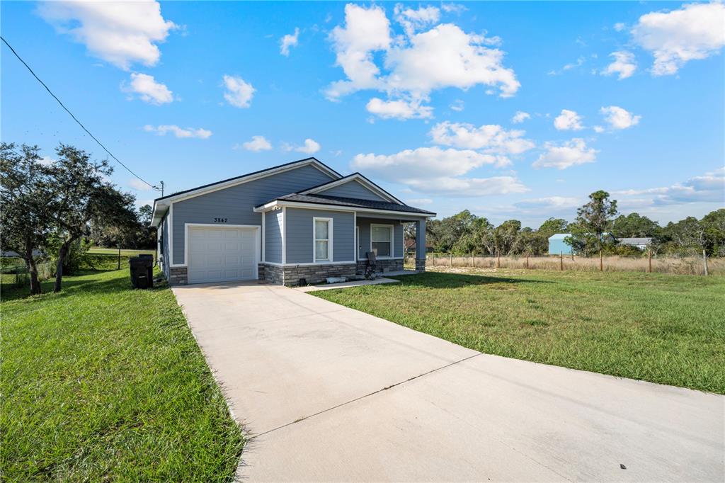 A blue single-story house with a garage and concrete driveway sits on a grassy lot — 3842 PHILLIPS ROAD, LAKE WALES, FL
