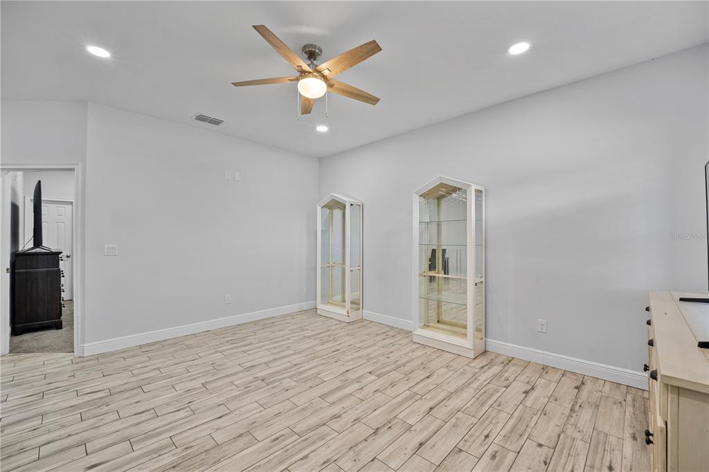 A room with light wood-look tile flooring, a ceiling fan, and two glass display cabinets — 3842 PHILLIPS ROAD, LAKE WALES, FL