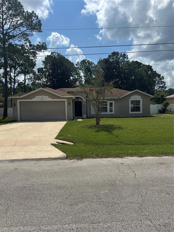 A single-story house with a two-car garage, a front lawn, and a paved driveway — 12 RIVERDALE LANE, PALM COAST, FL