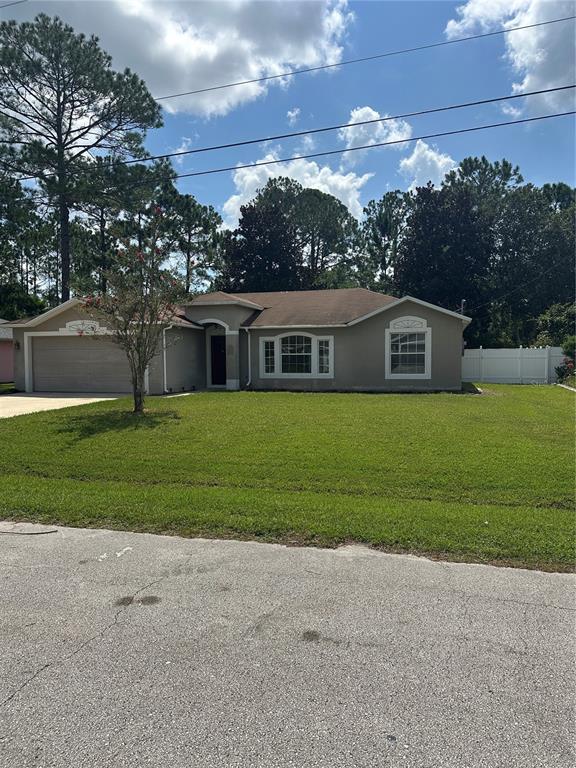 A single-story house with a beige stucco exterior, a two-car garage, and a front lawn — 12 RIVERDALE LANE, PALM COAST, FL