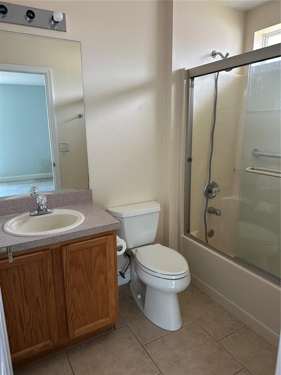 A bathroom features a wooden vanity, a toilet, and a shower-tub combination with glass doors — 12 RIVERDALE LANE, PALM COAST, FL