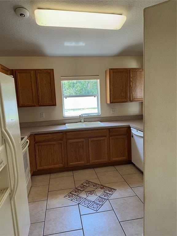A kitchen with wood cabinets, a white sink, and tiled floors with a decorative inlay — 12 RIVERDALE LANE, PALM COAST, FL