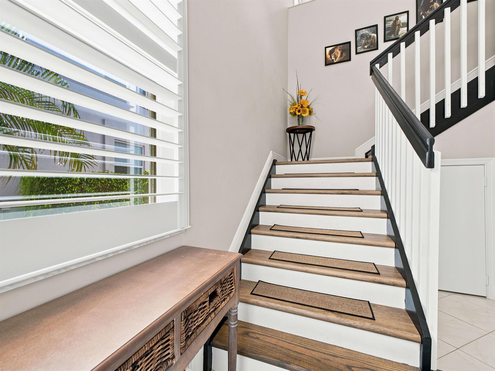 A staircase with wooden treads and white risers features a black railing and runner rugs — 7960 Laina Lane Unit 3, Boynton Beach FL 33437, BOYNTON BEACH, FL