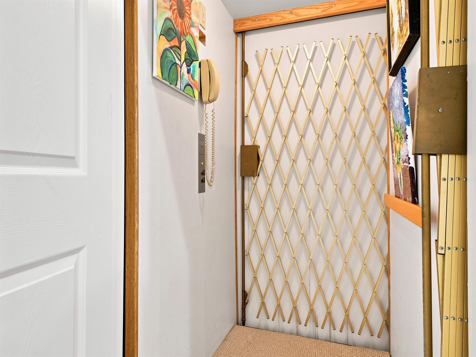 A small entryway features a beige accordion security gate, a wall-mounted telephone, and artwork — 7960 Laina Lane Unit 3, Boynton Beach FL 33437, BOYNTON BEACH, FL