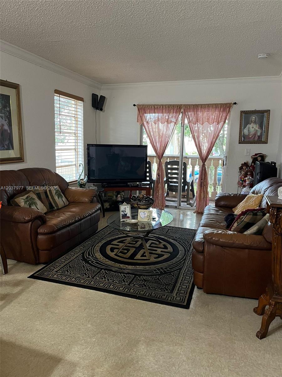 A living room features two brown leather sofas, a glass coffee table, and sliding glass doors — 525 W 69th St # 207, Hialeah FL 33014, HIALEAH, FL