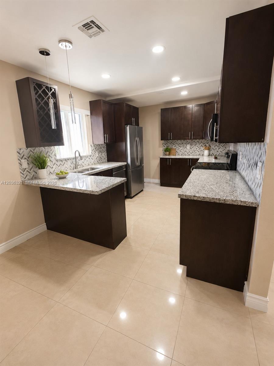 A kitchen features dark wood cabinets, granite countertops, a tile backsplash, and light-colored floor tiles — 4011 SW 28th St # 0, West Park FL 33023, WEST PARK, FL