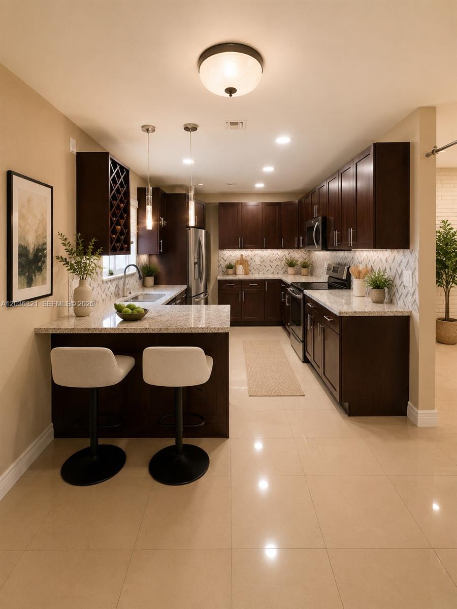 A kitchen features dark wood cabinets, granite countertops, a breakfast bar, and light tile flooring — 4011 SW 28th St # 0, West Park FL 33023, WEST PARK, FL