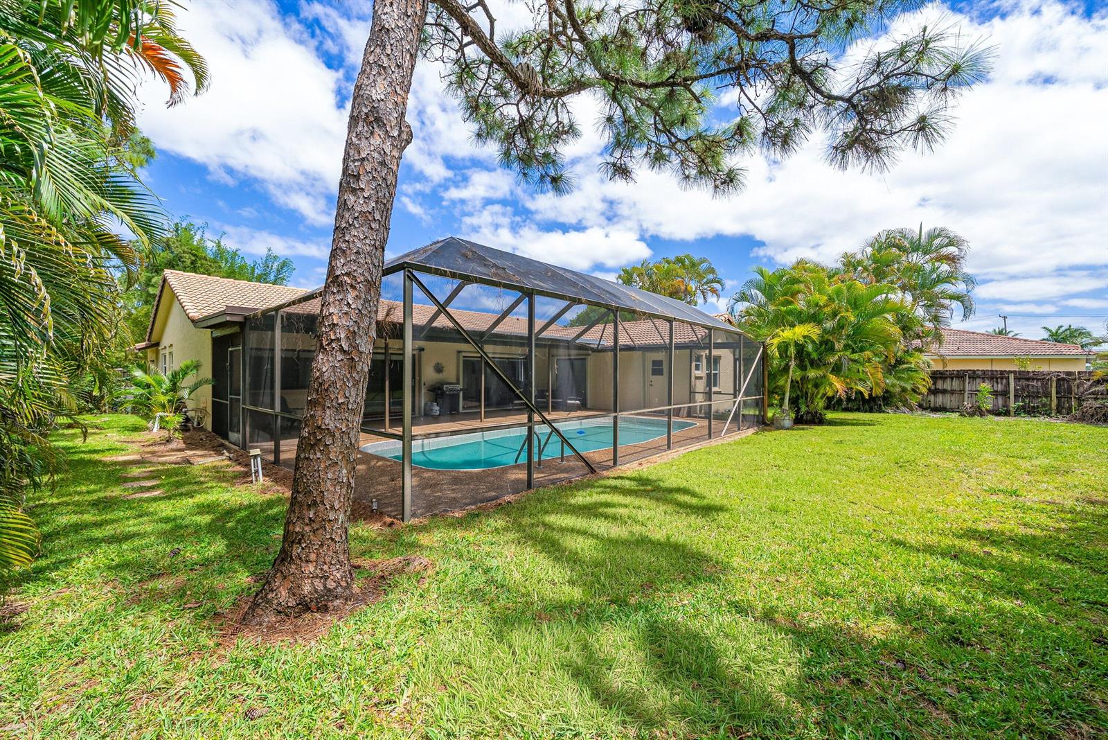 A backyard features a swimming pool enclosed by a screened lanai next to a house — 2493 Timbercreek Circle NW, Boca Raton FL 33431, BOCA RATON, FL