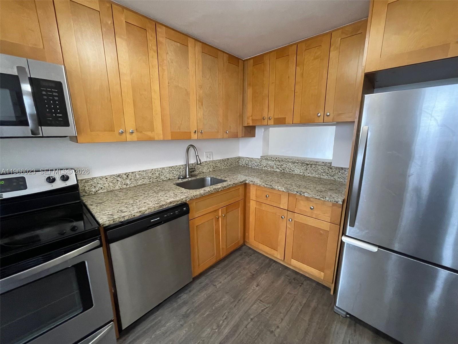 A kitchen features light wood cabinets, granite countertops, and stainless steel appliances — 4700 Washington St # 507, Hollywood FL 33021, HOLLYWOOD, FL