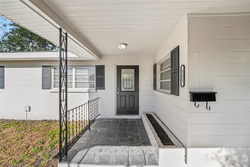 The front entrance features a covered porch with a tiled floor, black door, and planter — 521 W PALMEDEN DRIVE, LAKELAND, FL