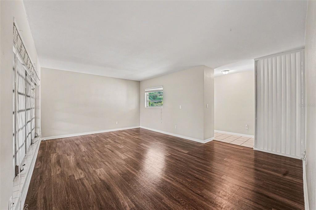 An empty room with wood-look flooring, beige walls, two windows, and a tiled entryway — 521 W PALMEDEN DRIVE, LAKELAND, FL