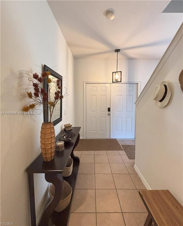 An entryway features tile flooring, a console table with decor, and a double front door — 8042 Silver Birch Way, Lehigh Acres FL 33971, LEHIGH ACRES, FL