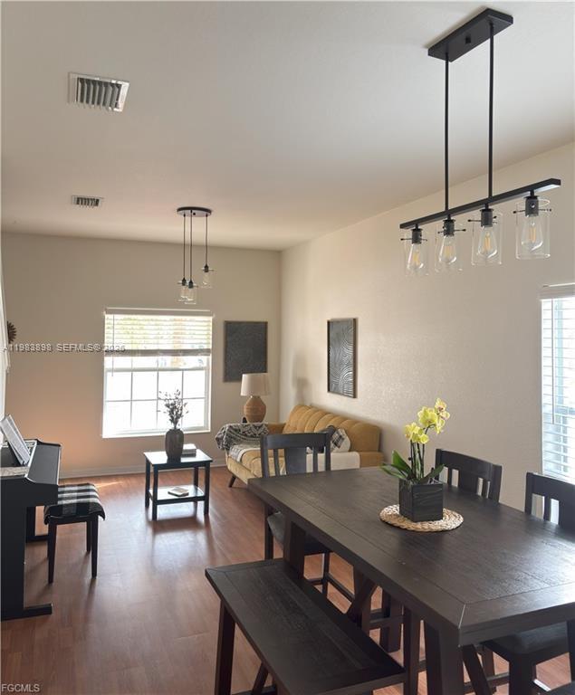A dining area with a dark wood table and chairs opens into a living space — 8042 Silver Birch Way, Lehigh Acres FL 33971, LEHIGH ACRES, FL