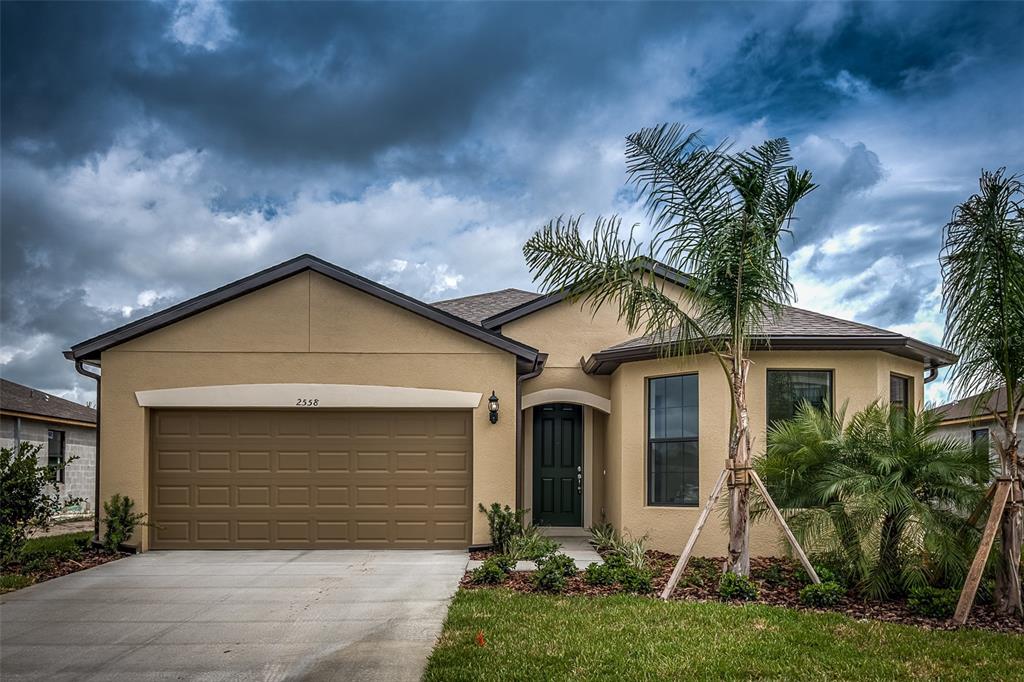 A single-story tan house with a two-car garage and a palm tree in the front — 2558 SHERMAN OAK DRIVE, NORTH PORT, FL