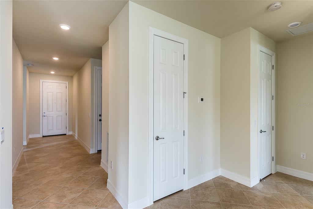 A hallway with beige tile floors, white doors, and recessed lighting — 2558 SHERMAN OAK DRIVE, NORTH PORT, FL