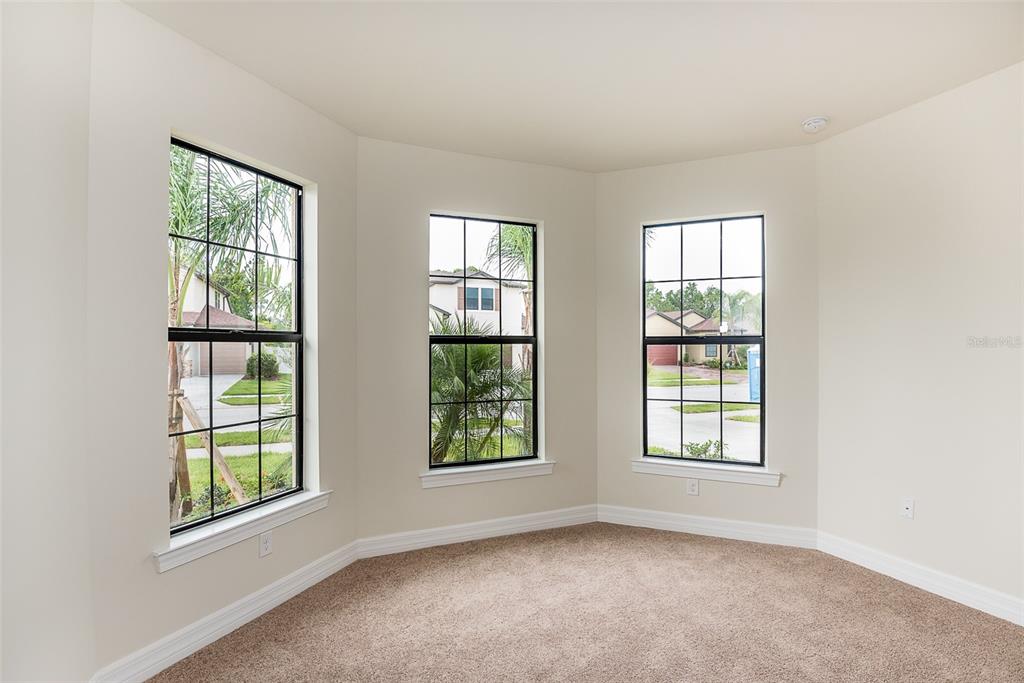 An empty room with beige carpet, white walls, and three windows with black frames — 2558 SHERMAN OAK DRIVE, NORTH PORT, FL