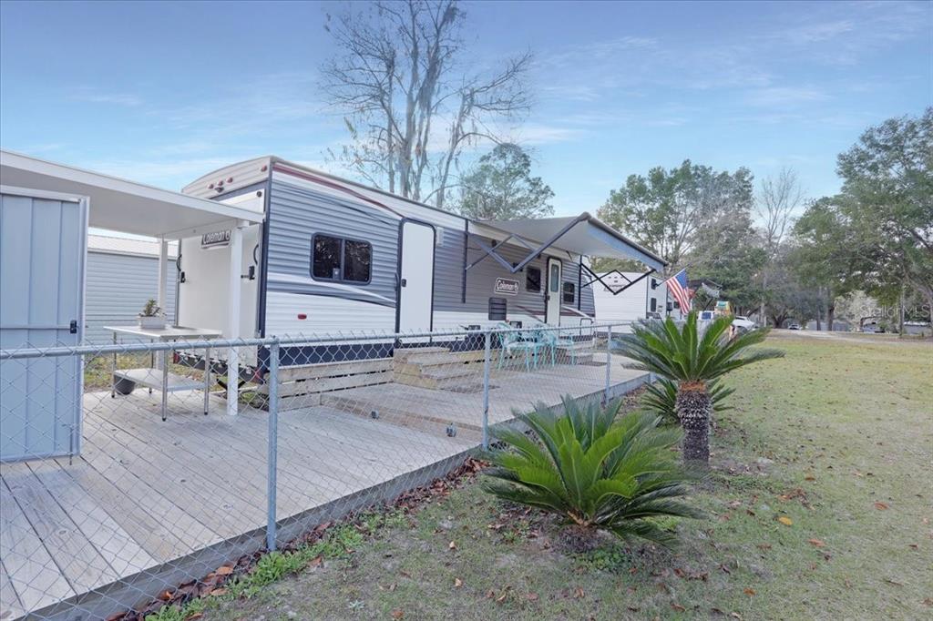 A Coleman travel trailer sits on a wooden deck behind a chain-link fence — 5336 SW COUNTY ROAD 791, LAKE BUTLER, FL