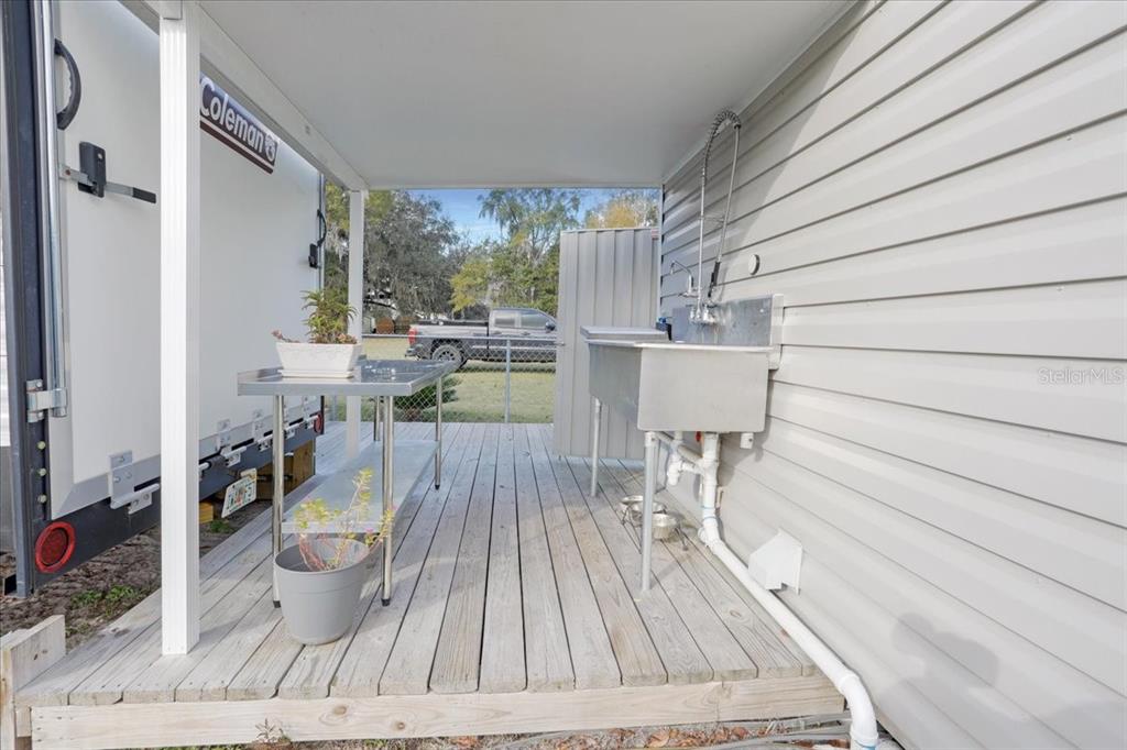 An outdoor covered deck features a stainless steel utility sink and a metal prep table — 5336 SW COUNTY ROAD 791, LAKE BUTLER, FL