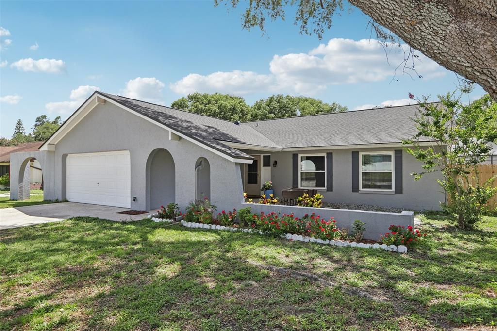 A gray single-story house with a white garage door and a low front garden wall — 1009 BLACK KNIGHT DRIVE, VALRICO, FL