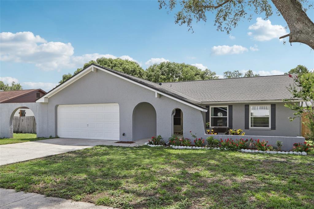 A single-story gray house with a two-car garage, arched entryway, and a front garden bed — 1009 BLACK KNIGHT DRIVE, VALRICO, FL
