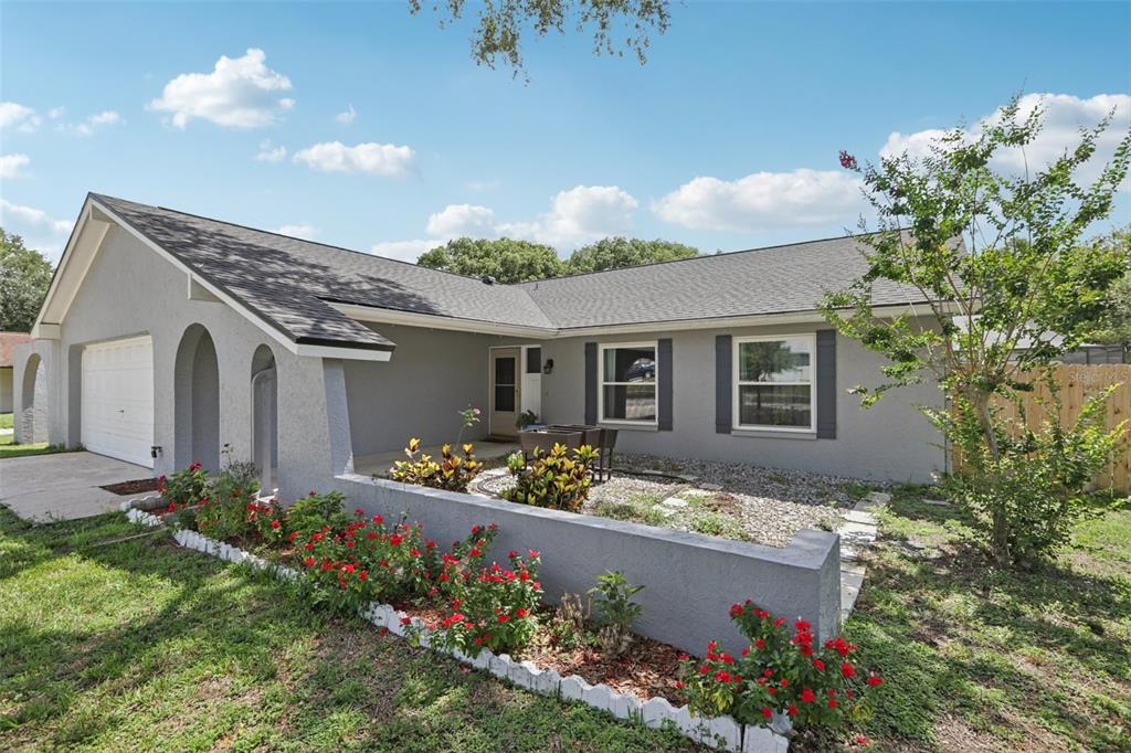 A gray single-story house with a garage, arched entryway, and a front garden bed — 1009 BLACK KNIGHT DRIVE, VALRICO, FL