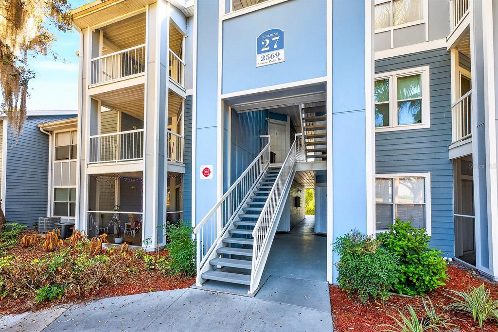 An exterior view of a blue apartment building with a central staircase and balconies — 2569 GRASSY POINT DRIVE UNIT 207, LAKE MARY, FL