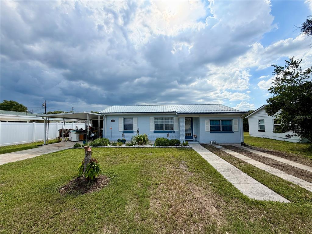 A light blue single-story house features a metal roof, a carport, and a concrete driveway — 1185 S JOHNSON AVENUE, BARTOW, FL