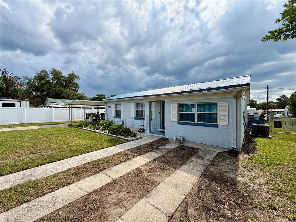 A light blue single-story house with a metal roof and a concrete driveway — 1185 S JOHNSON AVENUE, BARTOW, FL