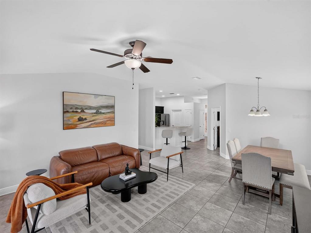 A living room and dining area with tile floors, a leather sofa, and a ceiling fan — 14453 BARLEY FIELD DRIVE, WIMAUMA, FL
