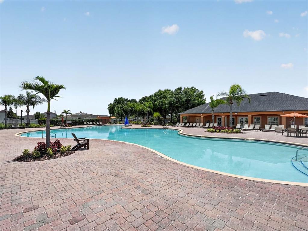 A large outdoor swimming pool with a brick paver deck and a clubhouse building — 14453 BARLEY FIELD DRIVE, WIMAUMA, FL