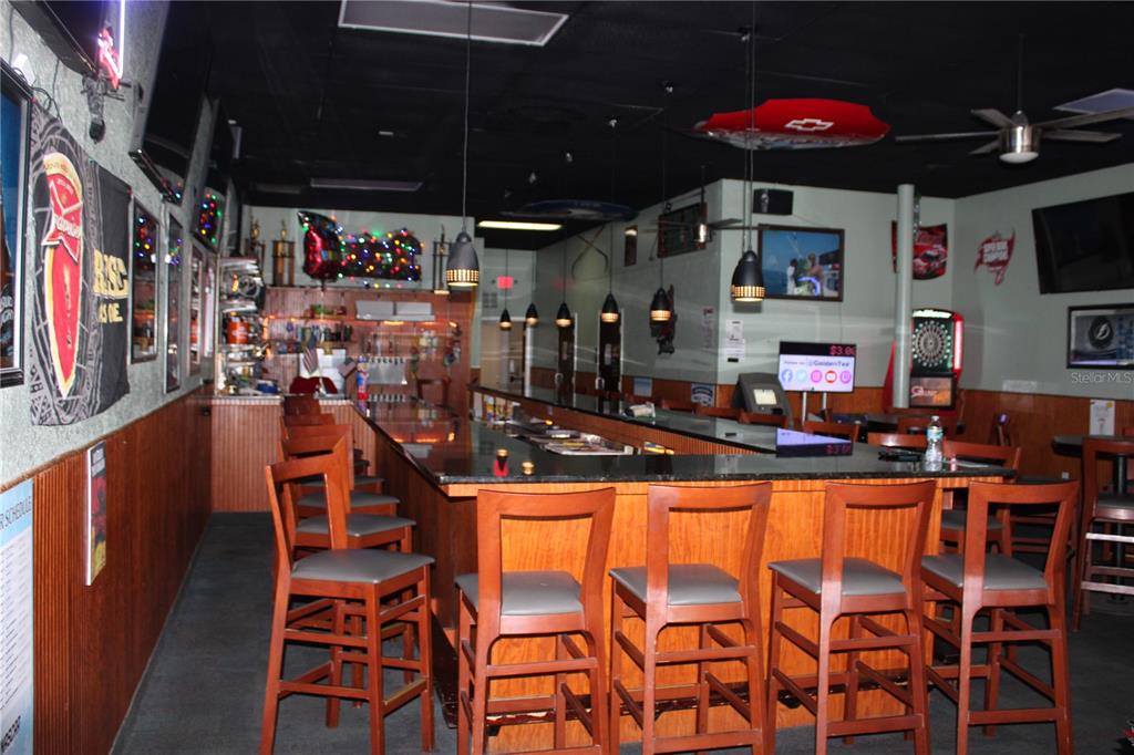 A bar interior features a long black countertop, wooden stools, and various wall decorations — 6636 RIDGE ROAD, PORT RICHEY, FL