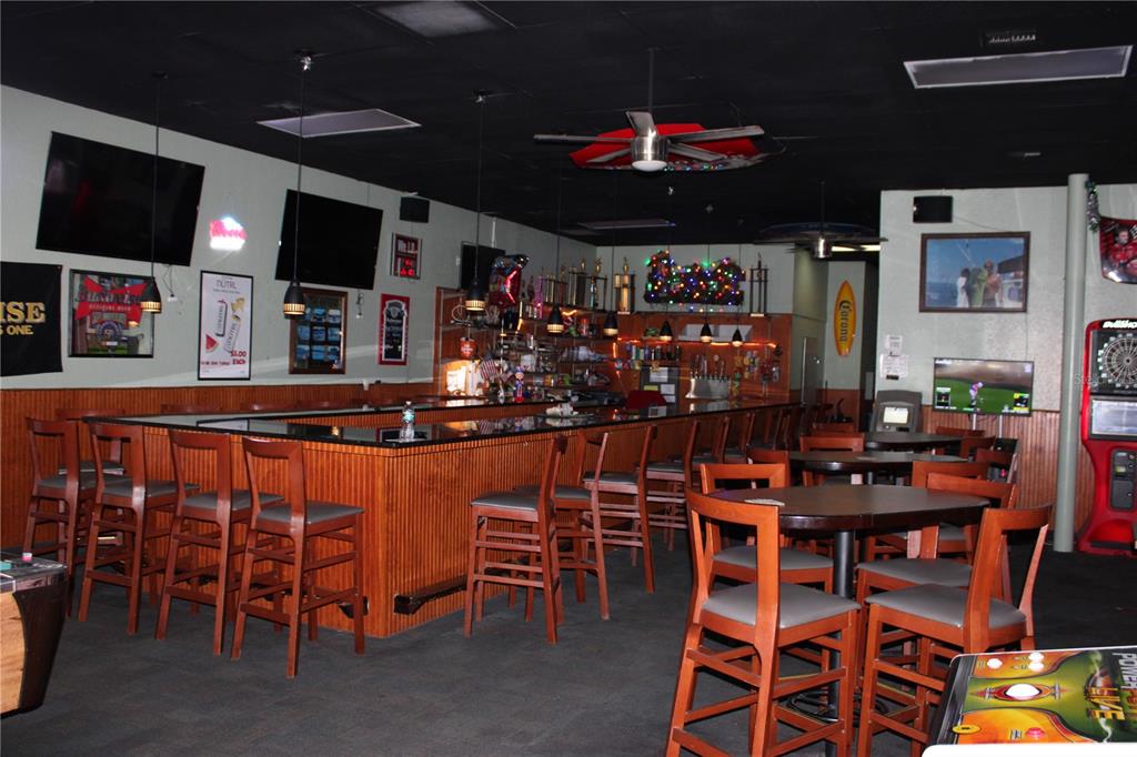 A bar interior features a long wooden counter, high-top tables, chairs, and multiple television screens — 6636 RIDGE ROAD, PORT RICHEY, FL