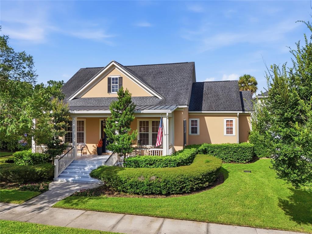A tan house with a front porch, a grey roof, and manicured hedges — 1018 WILD ELM STREET, CELEBRATION, FL