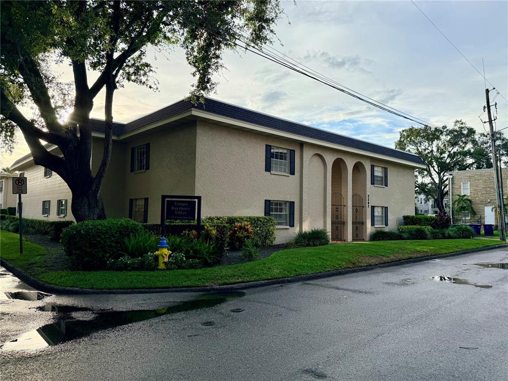 A two-story apartment building with a beige stucco exterior and arched entryway stands near trees — 2207 S CAROLINA AVENUE UNIT 33, TAMPA, FL
