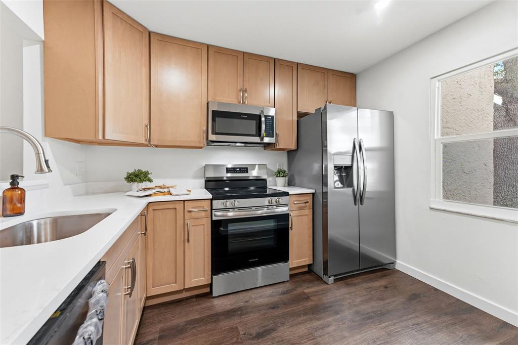 A kitchen features light wood cabinets, stainless steel appliances, and dark wood-look flooring — 11511 113TH STREET UNIT 2D, LARGO, FL