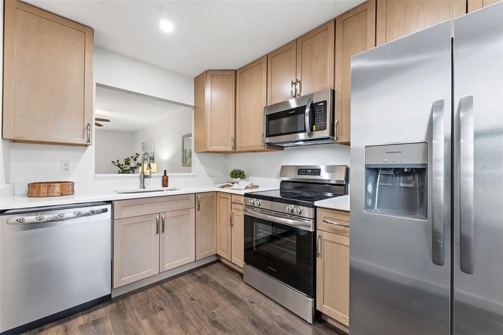 A kitchen features light wood cabinets, stainless steel appliances, and white countertops — 11511 113TH STREET UNIT 2D, LARGO, FL