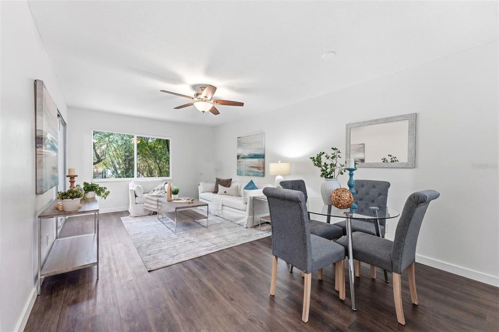 A living and dining area features dark wood-look flooring, a ceiling fan, and neutral furniture — 11511 113TH STREET UNIT 2D, LARGO, FL