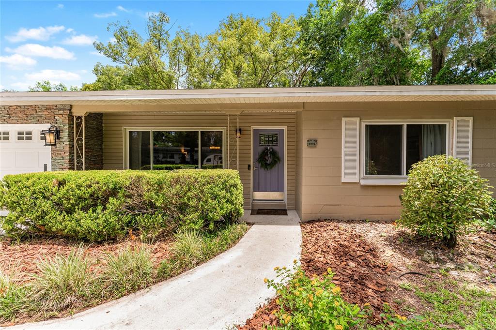 A single-story house features tan siding, a stone accent wall, and a purple front door — 3224 NW 31ST AVENUE, GAINESVILLE, FL