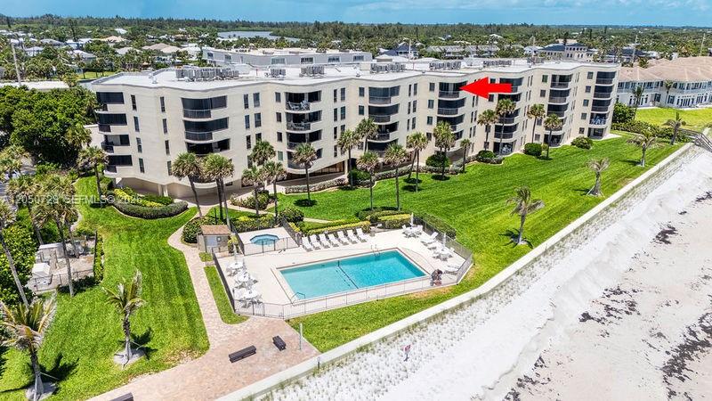 An aerial view shows a multi-story beachfront condominium building with a pool and palm trees — 4600 Highway A1a # 507, Vero Beach FL 32963, VERO BEACH, FL
