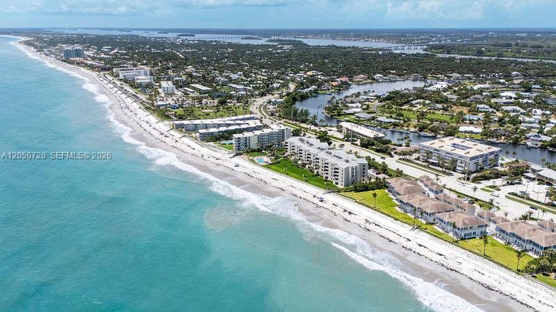 An aerial view shows beachfront condominiums along a coastline with a nearby waterway and bridge — 4600 Highway A1a # 507, Vero Beach FL 32963, VERO BEACH, FL