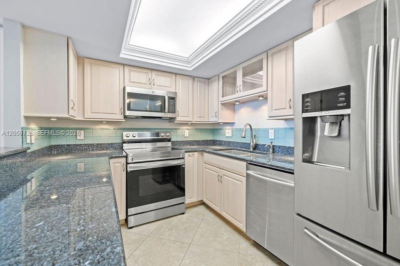 A kitchen featuring light wood cabinets, dark granite countertops, stainless steel appliances, and a skylight — 4600 Highway A1a # 507, Vero Beach FL 32963, VERO BEACH, FL