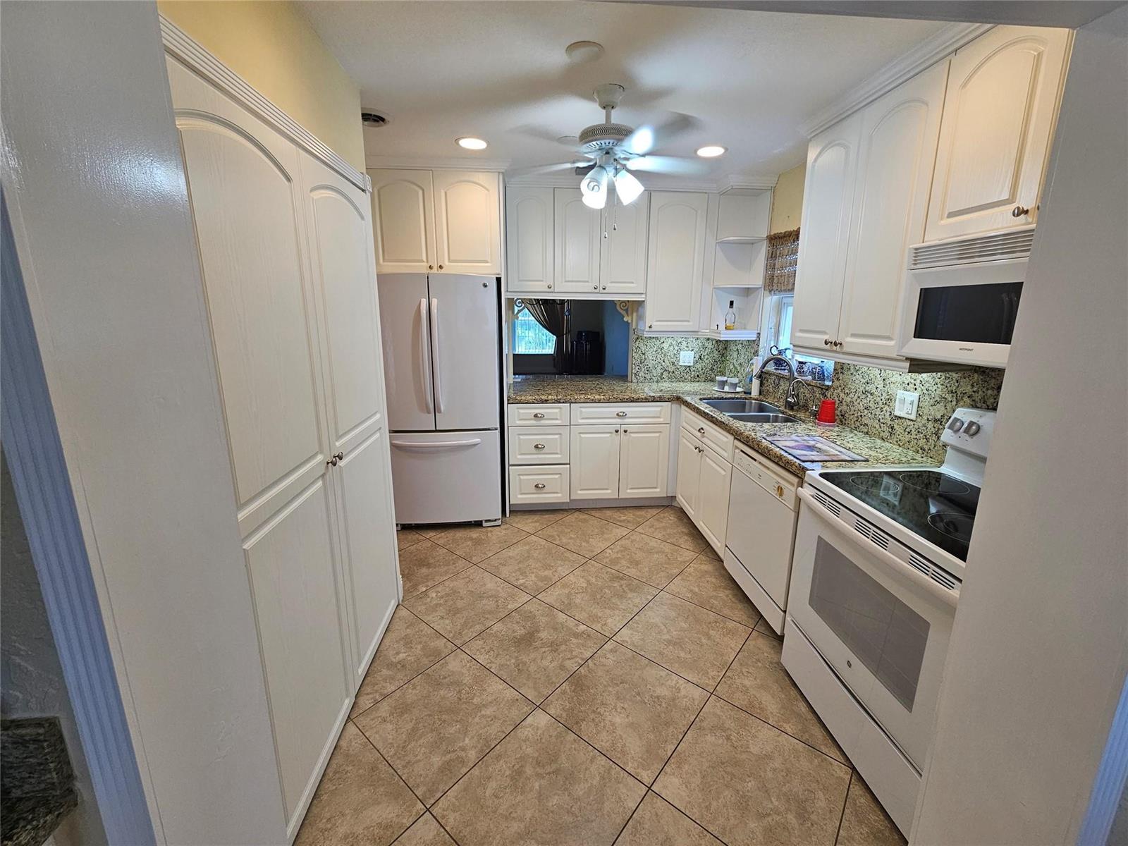 A kitchen features white cabinetry, granite countertops, stainless steel appliances, and diagonal tile flooring — 6650 Royal Palm Boulevard # 315c, Margate FL 33063, MARGATE, FL