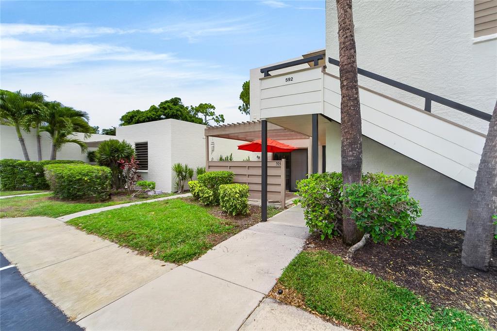 An exterior view of a two-story residential building with a staircase and a small patio — 593 LAKESIDE DRIVE UNIT 593, BRADENTON, FL