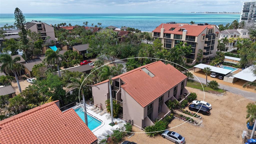 An aerial view shows a multi-story tan building with a red tile roof and pool — 218 PASS KEY ROAD UNIT 218, SARASOTA, FL